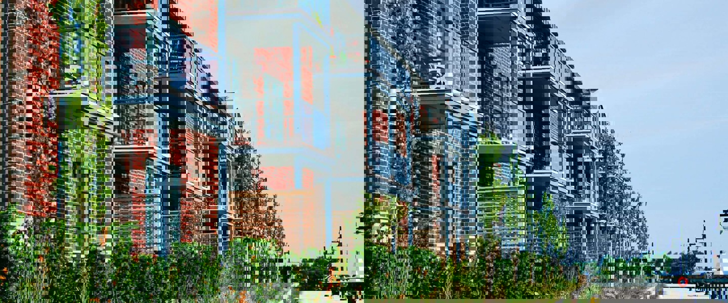 Moderne appartementencomplexen met balkons, omringd door groen, aan een rustige promenade.