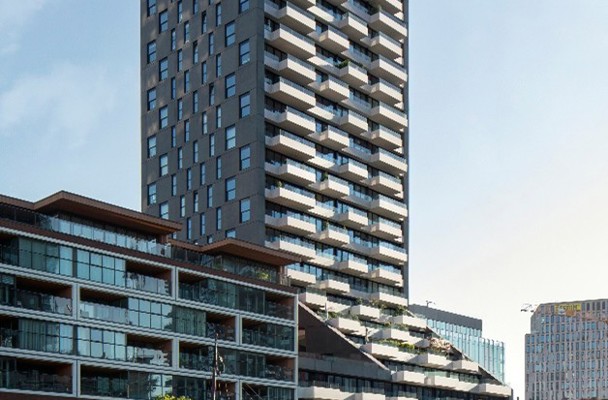 Moderne flat met glazen gevel en balkonunits, naast een lager winkel- en appartementencomplex.