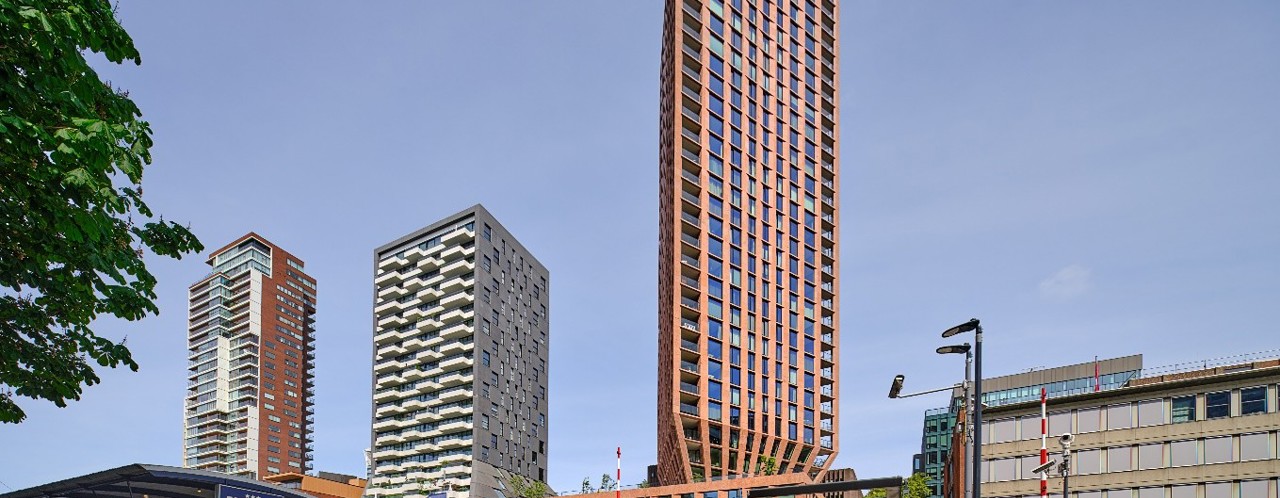 Moderne gebouwen in een stedelijke omgeving, met een opvallende hoge oranje toren op de voorgrond.
