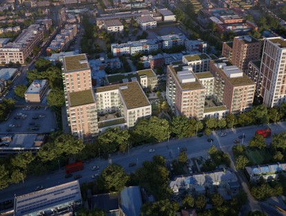 Aerial view of a modern residential area with green roofs, surrounded by trees and a busy street with traffic.