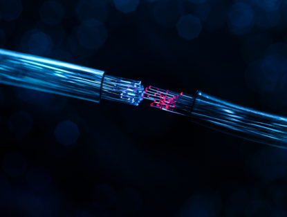 Glanzende glasvezelkabels die in het donker met elkaar verbinding maken, met een blauw uiteinde en een rood uiteinde.