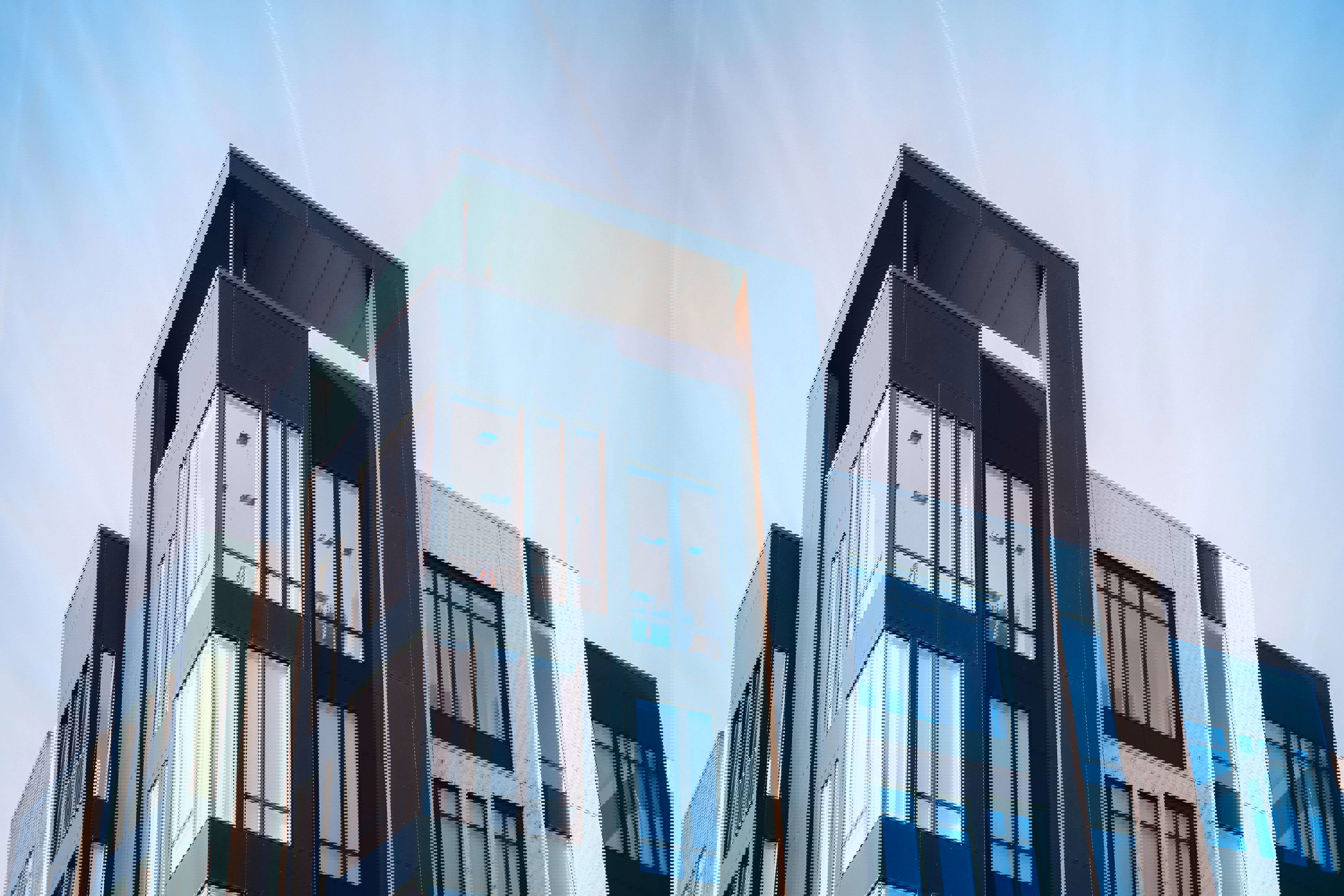 Moderne appartementencomplex met grote ramen en een strakke, donkergekleurde gevel, tegen een heldere blauwe lucht.