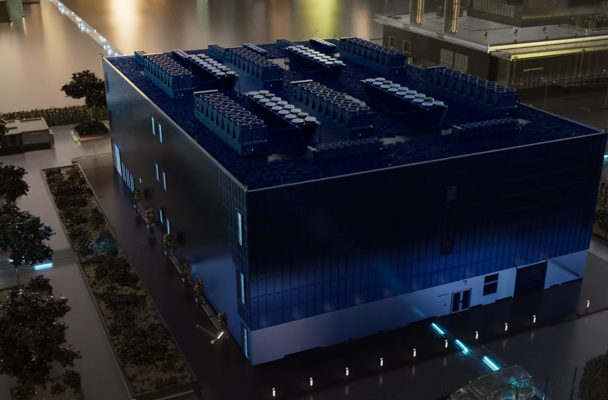 Modern, square blue commercial building with solar panels on the roof, located in an urban setting.