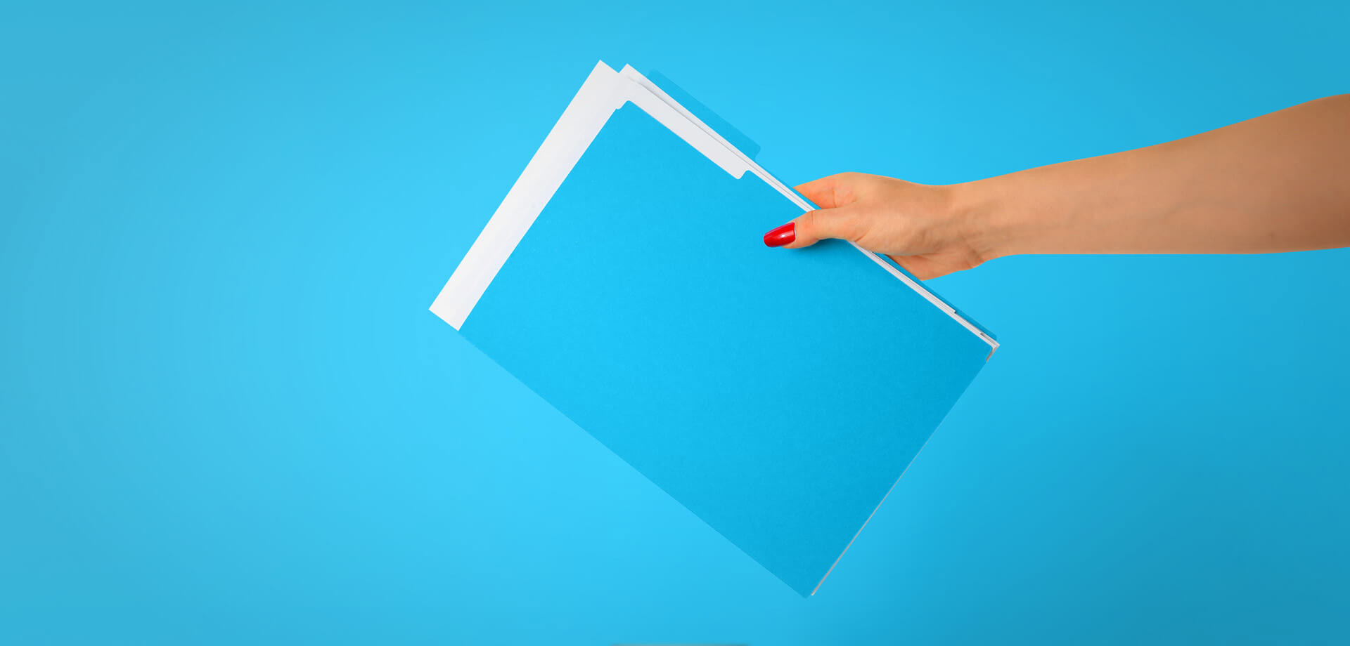 Een hand houdt een stapel blauwe mappen voor een heldere blauwe achtergrond.