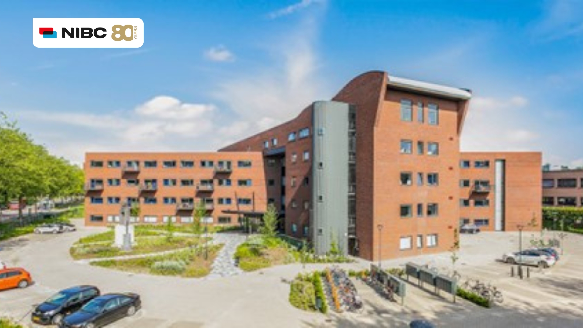 Modern kantoorgebouw omringd door groen, met het logo van NIBC zichtbaar linksboven.