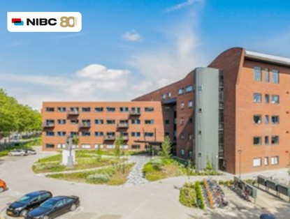 Modern office building surrounded by greenery, with the NIBC logo prominently displayed in the upper left corner.