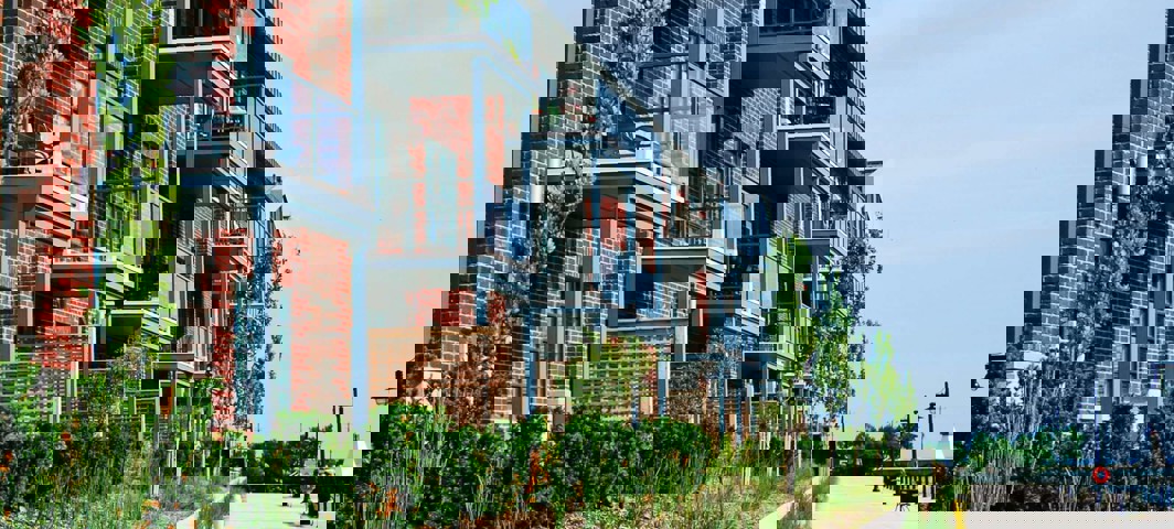 Moderne appartementencomplexen met balkons, omringd door groen, aan een rustige promenade.