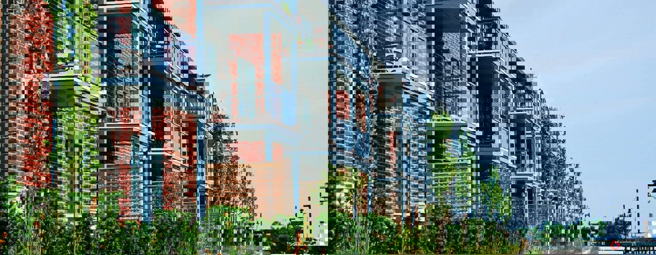 Moderne appartementencomplexen met balkons, omringd door groen, aan een rustige promenade.