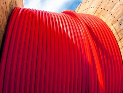Thick red cable rolled up in a wooden casing, ready for use in a construction project.