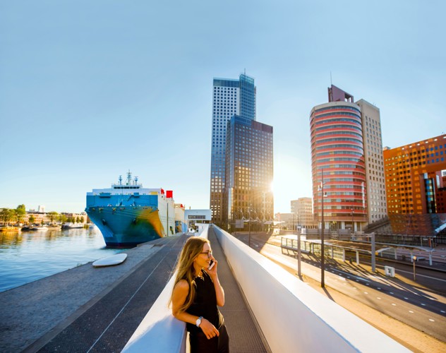 Urban view of a harbor with a large ship and modern buildings in the background, illuminated by the sunset.