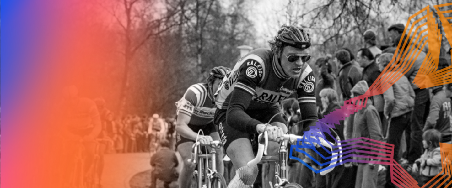 Fietser in zwart-wit met een menigte kijkers op de achtergrond, waarschijnlijk tijdens een wielerwedstrijd.