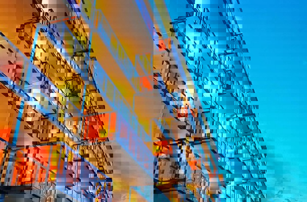 Moderne appartementsgebouwen met verlichte balkons in de avondlucht onder een heldere blauwe hemel.