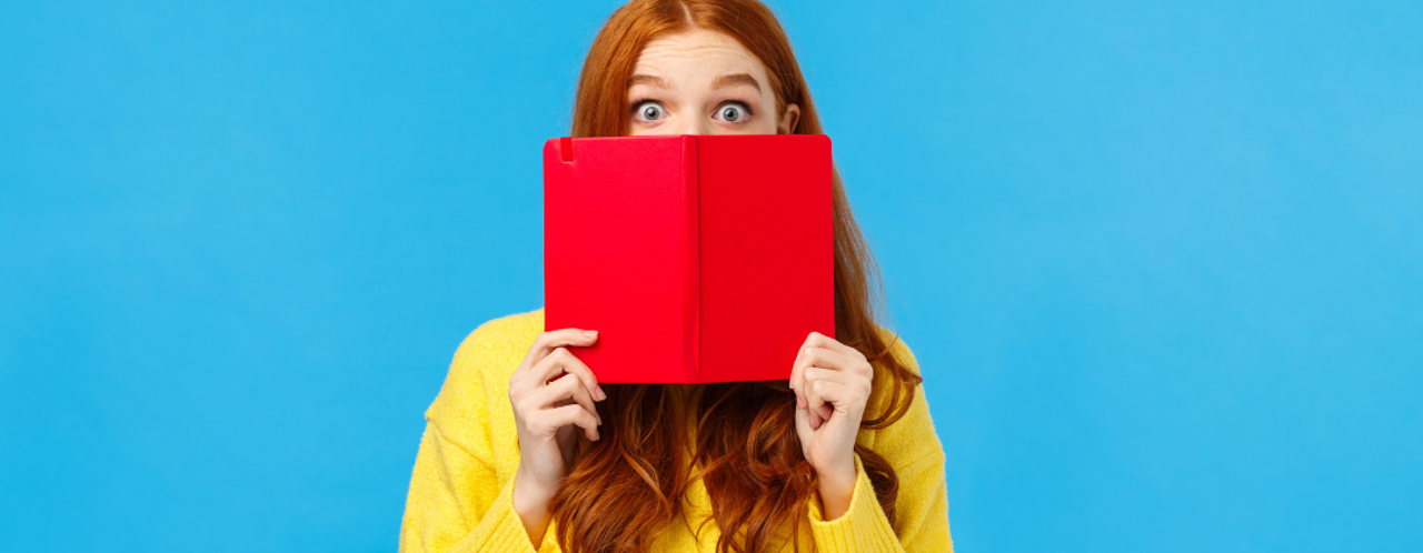 Vrouw met lange, golvende roestbruine haren die een felrode tablet vasthoudt voor een blauwe achtergrond.