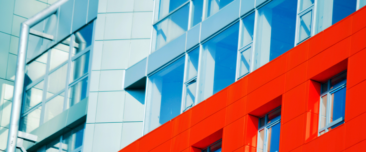 Detail of a building with a bright red facade and extensive glass, highlighting modern architecture.