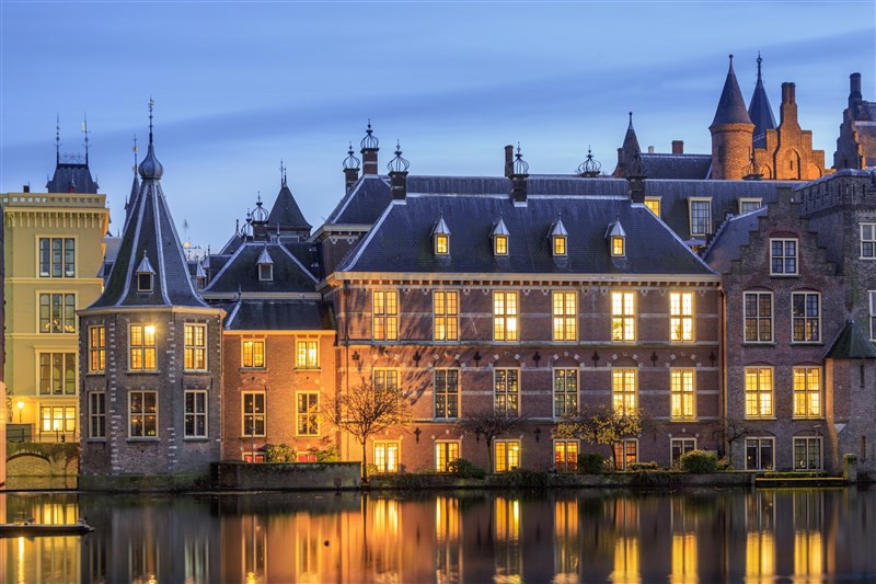 Historisch gebouw aan het water met verlichte ramen tijdens de schemering in Den Haag.