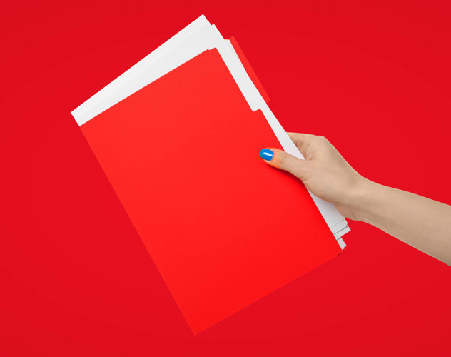 Hand die een stapel rode mappen vasthoudt tegen een heldere rode achtergrond.