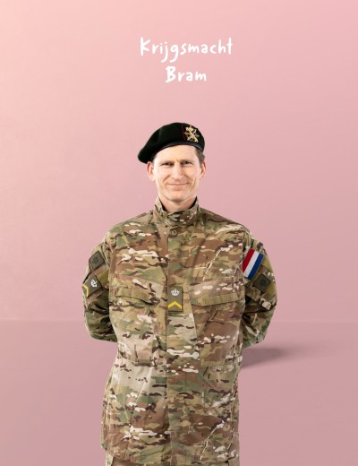 Kledij van de Krijgsmacht met Nederlandse vlag op de schouder, tegen een roze achtergrond.