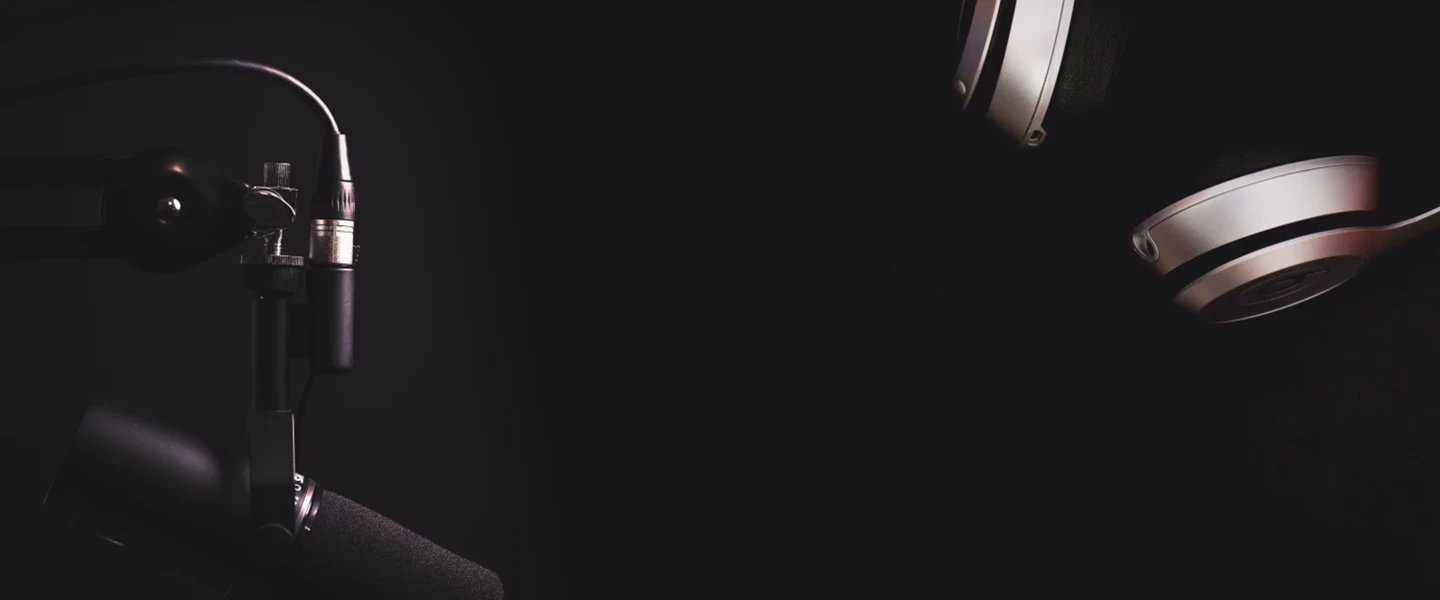 Zwarte achtergrond met een microfoon en een koptelefoon, klaar voor opnames of radioprogramma's.