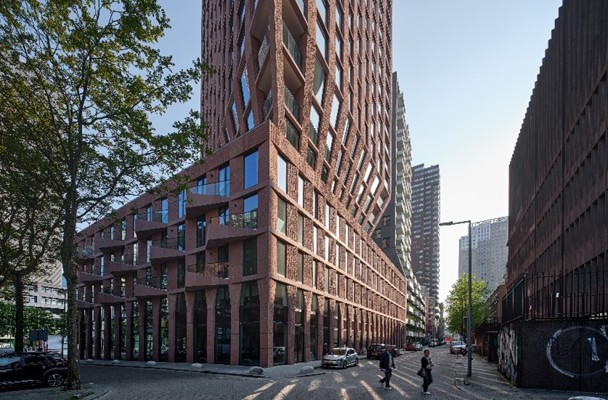 Moderne, opvallende architectuur van een toren met een gewelfde façade, gelegen aan een straat omzoomd met bomen en voetgangers.