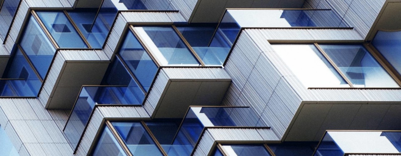 Close-up van een modern appartementencomplex met een golvende gevel en talrijke glazen balkons.