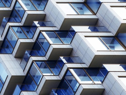 Close-up of a modern apartment building with a wavy facade and numerous glass balconies.