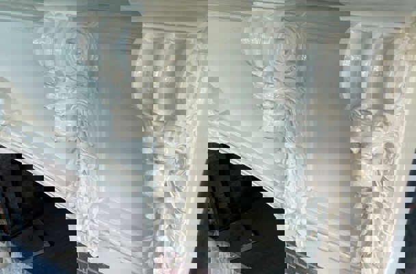 Gedetailleerde, wit geschilderde schoorsteenmantel met leeuwenkoppen als beeldhouwwerk aan de zijkanten.