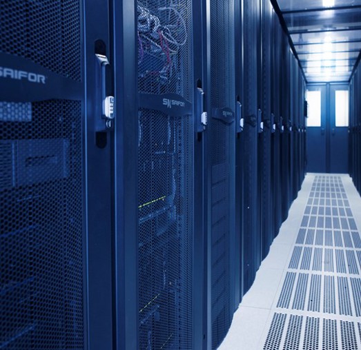A hallway with server racks in a data center, featuring blue lighting and a clean floor.