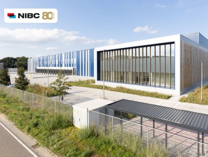 Modern office buildings with large windows and blue panels, situated along a street and surrounded by greenery.