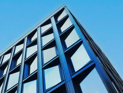 Modern office facade with large rectangular windows and a blue sky in the background.