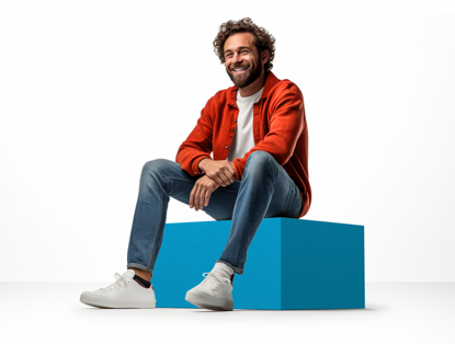 Jongen in een feloranje sweater zit op een turquoise blok en kijkt aandachtig naar de camera.