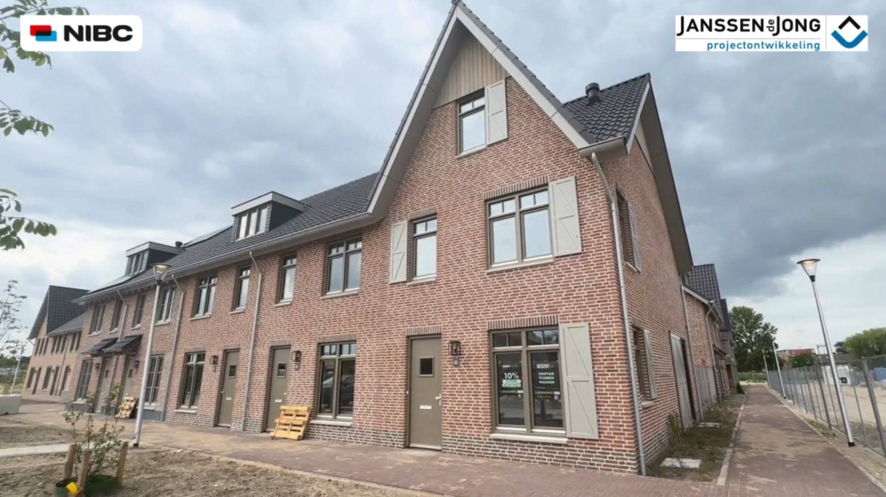 Moderne nieuwbouwwoningen met bakstenen gevels en moderne kozijnen in een straat onder een bewolkte lucht.