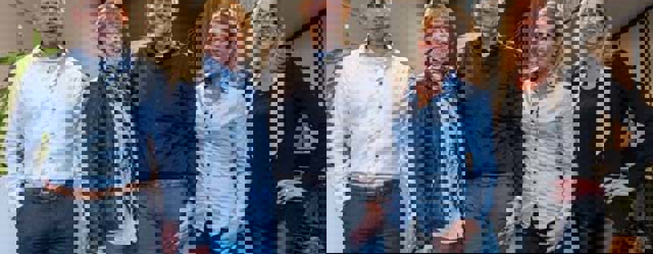 Vijf collega's in zakelijke kleding staan ontspannen in een kantooromgeving.