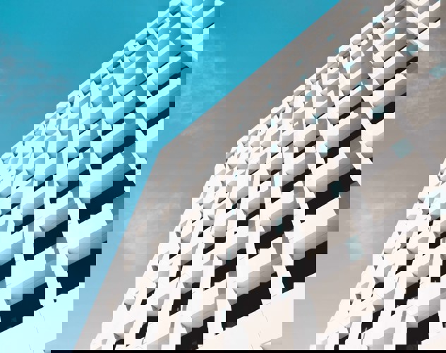 Moderne witte gevel van een gebouw met opvallende rechthoekige vensters onder een heldere blauwe lucht.