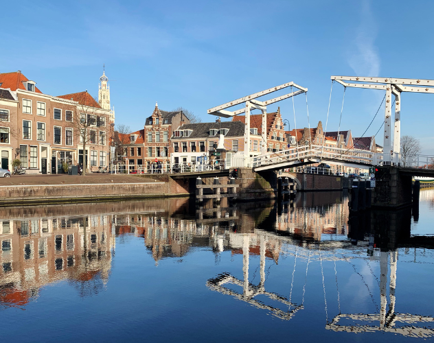 Historische gebouwen weerkaatst in een serene haven met een ophaalbrug.