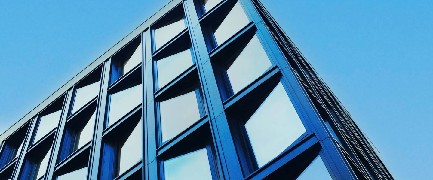 Modern kantoorgebouw met een blauwe glazen gevel en een opvallende architectuur.