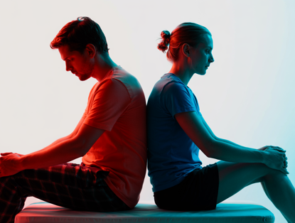 Twee mensen zitten rug aan rug, verlicht met contrasterende kleuren: de jongen in warme tinten en de vrouw in koele tinten.