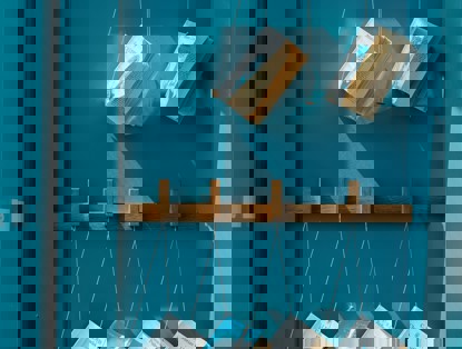 Een blauwe muur met houten haken en hangende boeken.