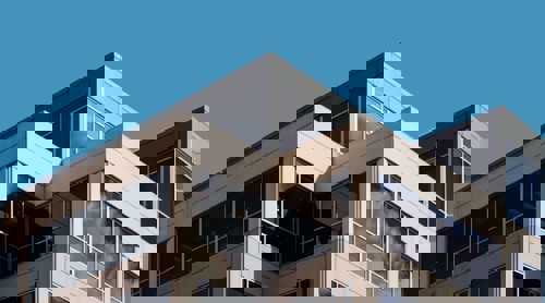 Hoek van een modern kantoorgebouw met grote ramen en een blauwe lucht.