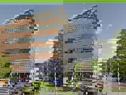 Kantoor van een modern advocatenkantoor, omringd door bomen en parkeerplaatsen.