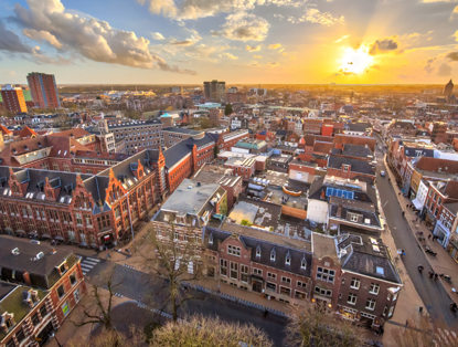 View of a city at sunset featuring historic buildings and modern architecture, with a colorful sky.