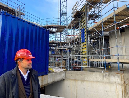 A construction site with scaffolding and containers, where a person wearing a hard hat is present.