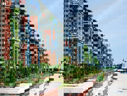 Moderne appartementencomplexen met balkons, omringd door groen, aan een rustige promenade.